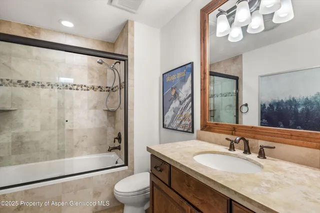 a bathroom with a granite countertop sink a toilet a mirror and shower