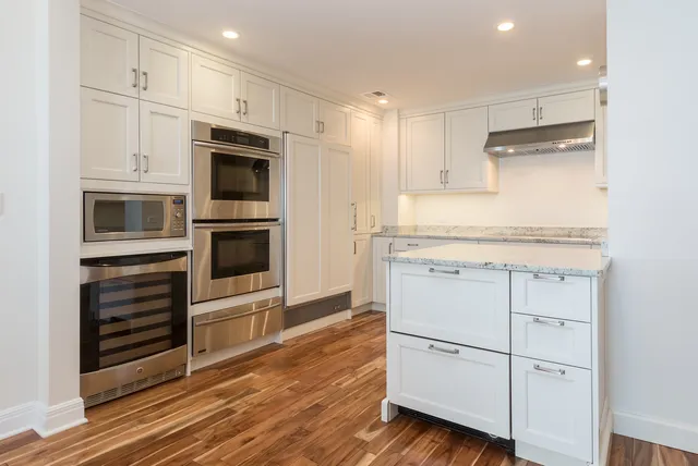 a kitchen with stainless steel appliances white cabinets and wooden floors