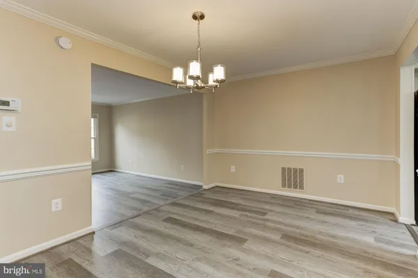 an empty room with wooden floor mirror and windows