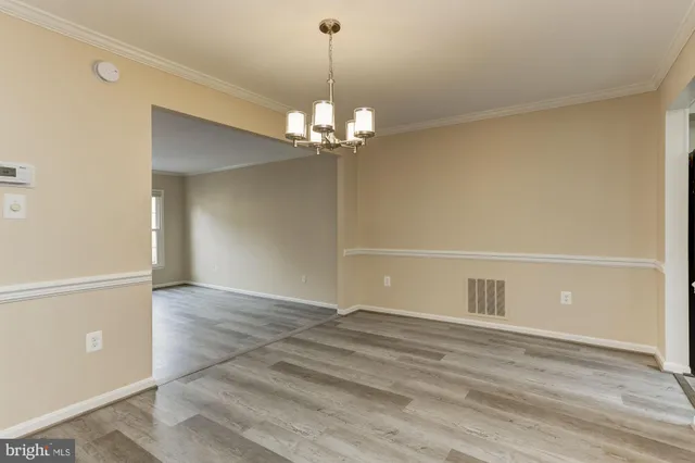 an empty room with wooden floor mirror and windows