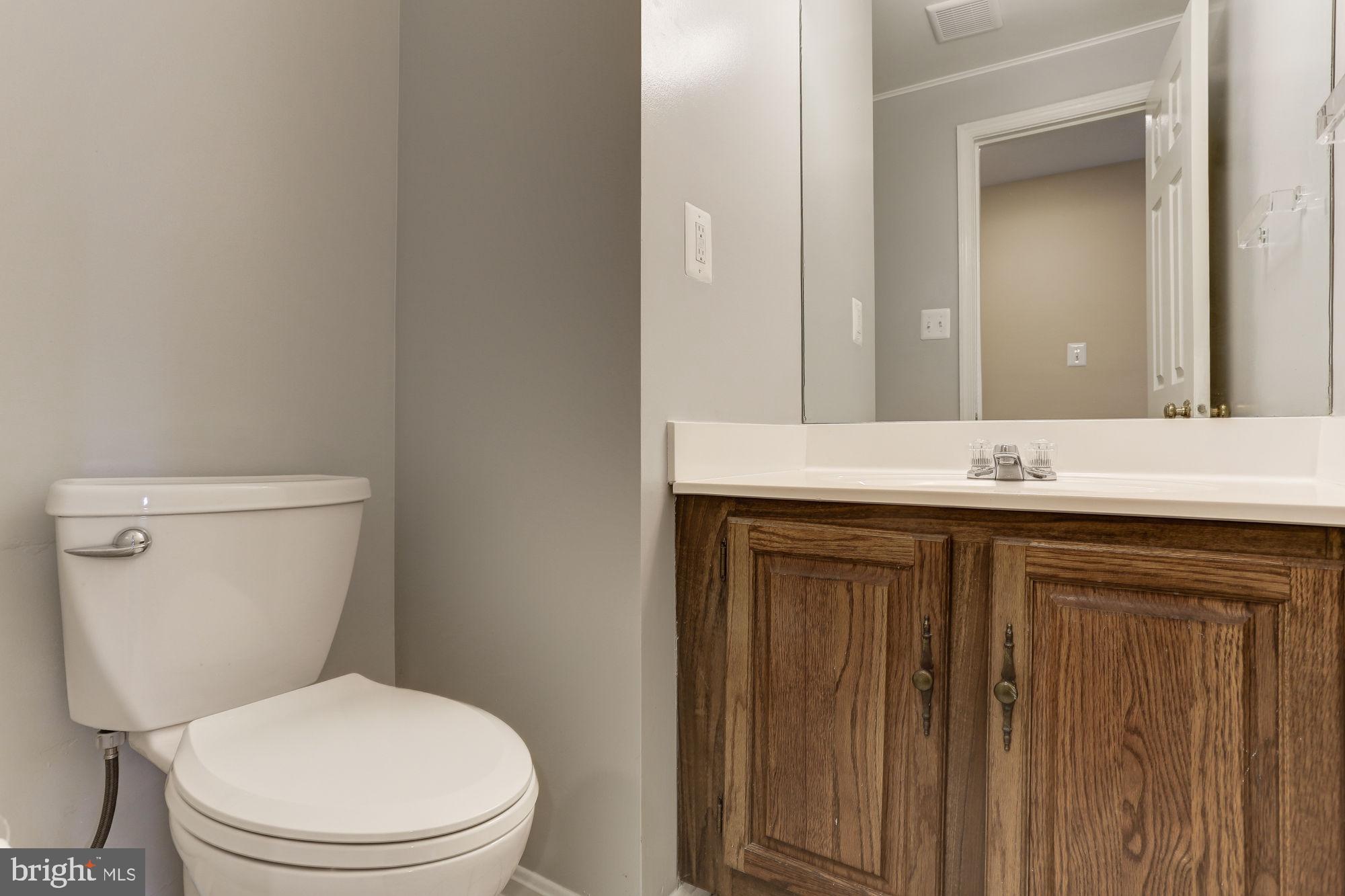 10107 Galsworthy Place Bethesda, MD 20817 - Photo 49 of 62 a bathroom with a granite countertop toilet sink and mirror