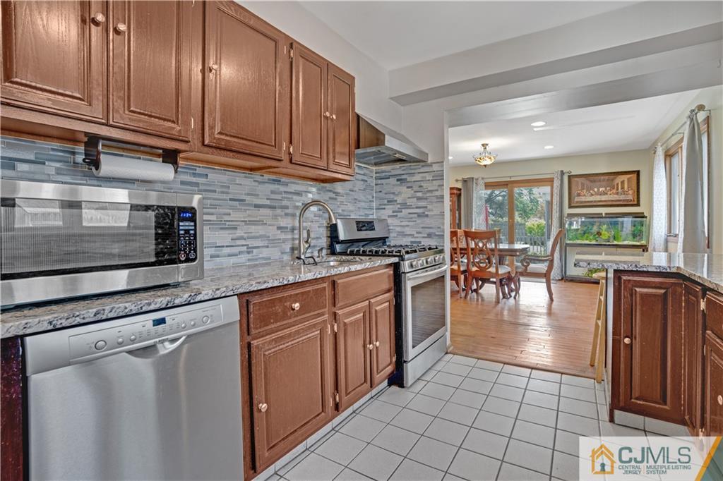 10 Crescent Road Edison, NJ 08817 - Photo 7 of 33 a kitchen with stainless steel appliances granite countertop a stove a sink dishwasher and cabinets with wooden floor
