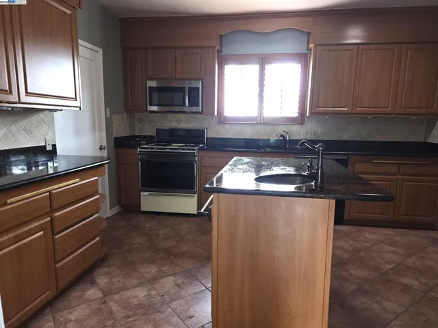 a kitchen with granite countertop a stove top oven microwave and cabinets