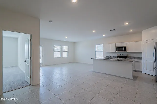 a view of kitchen with stainless steel appliances kitchen island granite countertop a refrigerator sink and white cabinets