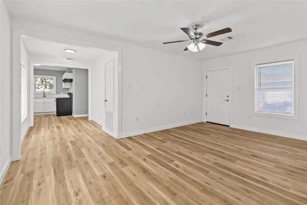 a view of empty room with wooden floor and ceiling fan