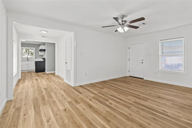 a view of empty room with wooden floor and ceiling fan