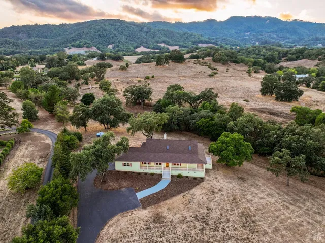 an aerial view of residential house with outdoor space and trees all around