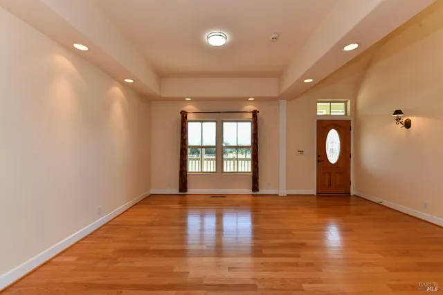 a view of an empty room with wooden floor and fan
