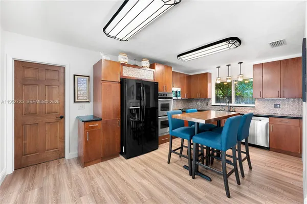 a kitchen with stainless steel appliances wooden floor dining table and chairs