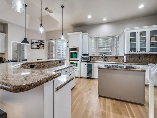a kitchen with stainless steel appliances granite countertop a sink a stove and a wooden floors