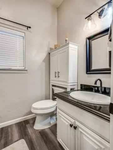 a bathroom with a granite countertop toilet sink and mirror