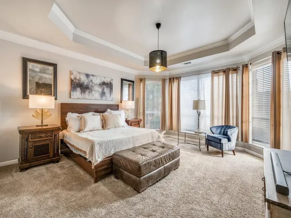 a spacious bedroom with a bed a couch and large window