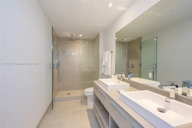 a bathroom with a double vanity sink toilet mirror and shower