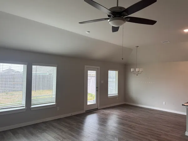 a view of an empty room with a window and wooden floor