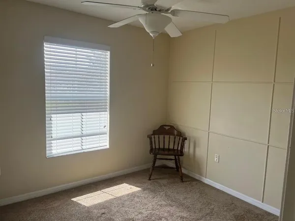 an empty room with windows and fan