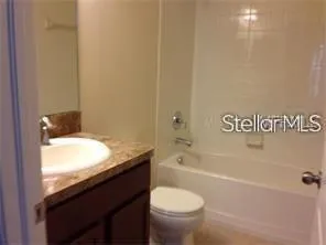 a bathroom with a granite countertop sink a toilet and bathtub