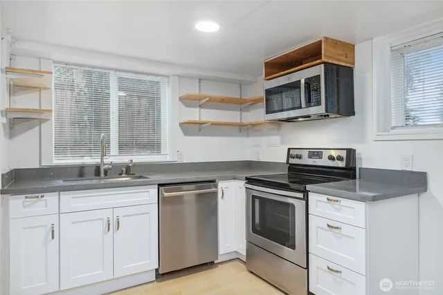 a kitchen with stainless steel appliances granite countertop white cabinets a sink and a stove