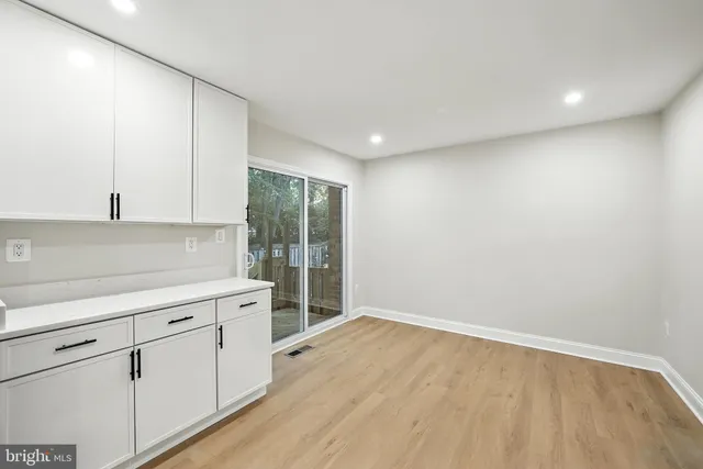 a kitchen with stainless steel appliances a refrigerator a sink a stove top oven cabinets and a dining table