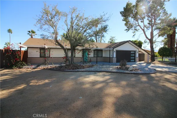 a front view of a house with yard and large tree