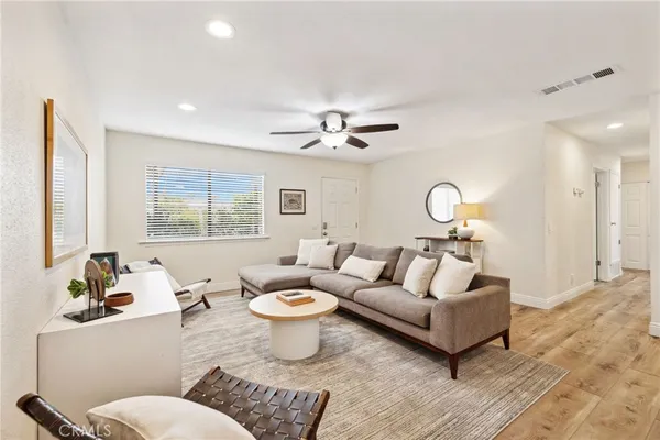 a living room with furniture kitchen view and a wooden floor