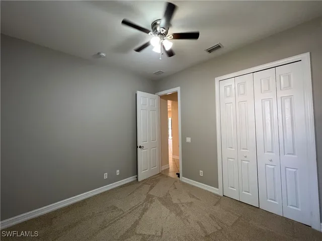 an empty room with closet and a ceiling fan