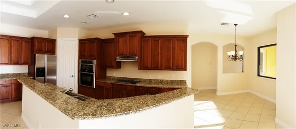a kitchen with kitchen island granite countertop a sink a stove and a refrigerator