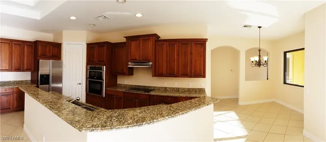 a kitchen with kitchen island granite countertop a sink a stove and a refrigerator