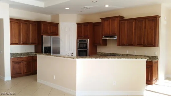 a kitchen with stainless steel appliances granite countertop a refrigerator and a stove top oven