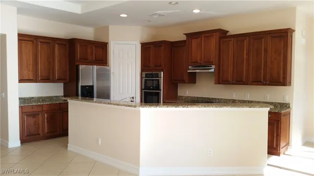 a kitchen with stainless steel appliances granite countertop a refrigerator and a stove top oven