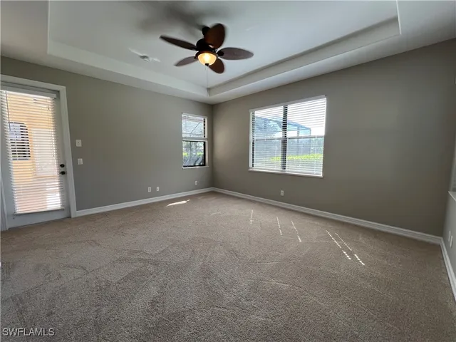 an empty room with windows and ceiling fan