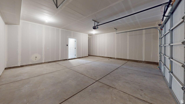 777 Pheasantbrook Drive, Unit 2B Centerville, UT 84014 - Photo 37 of 42 Spacious garage featuring a concrete floor, exposed drywall walls, recessed ceiling lighting, an automatic overhead door, and an interior access door