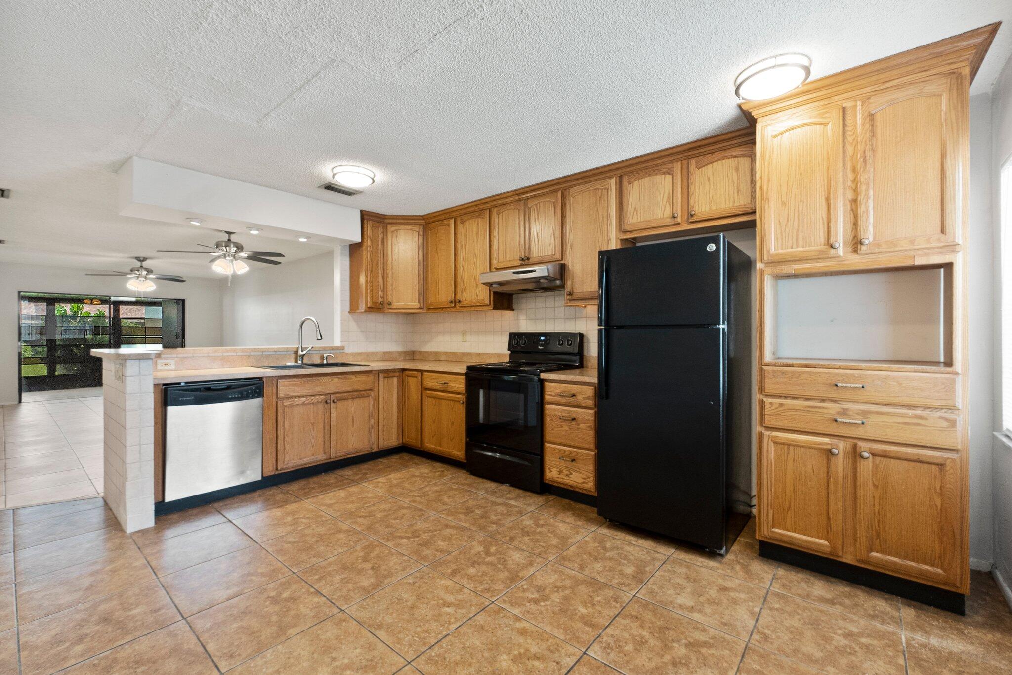 6012 Indrio Road, Unit E2 Fort Pierce, FL 34951 - Photo 11 of 25 a kitchen with a refrigerator sink and cabinets