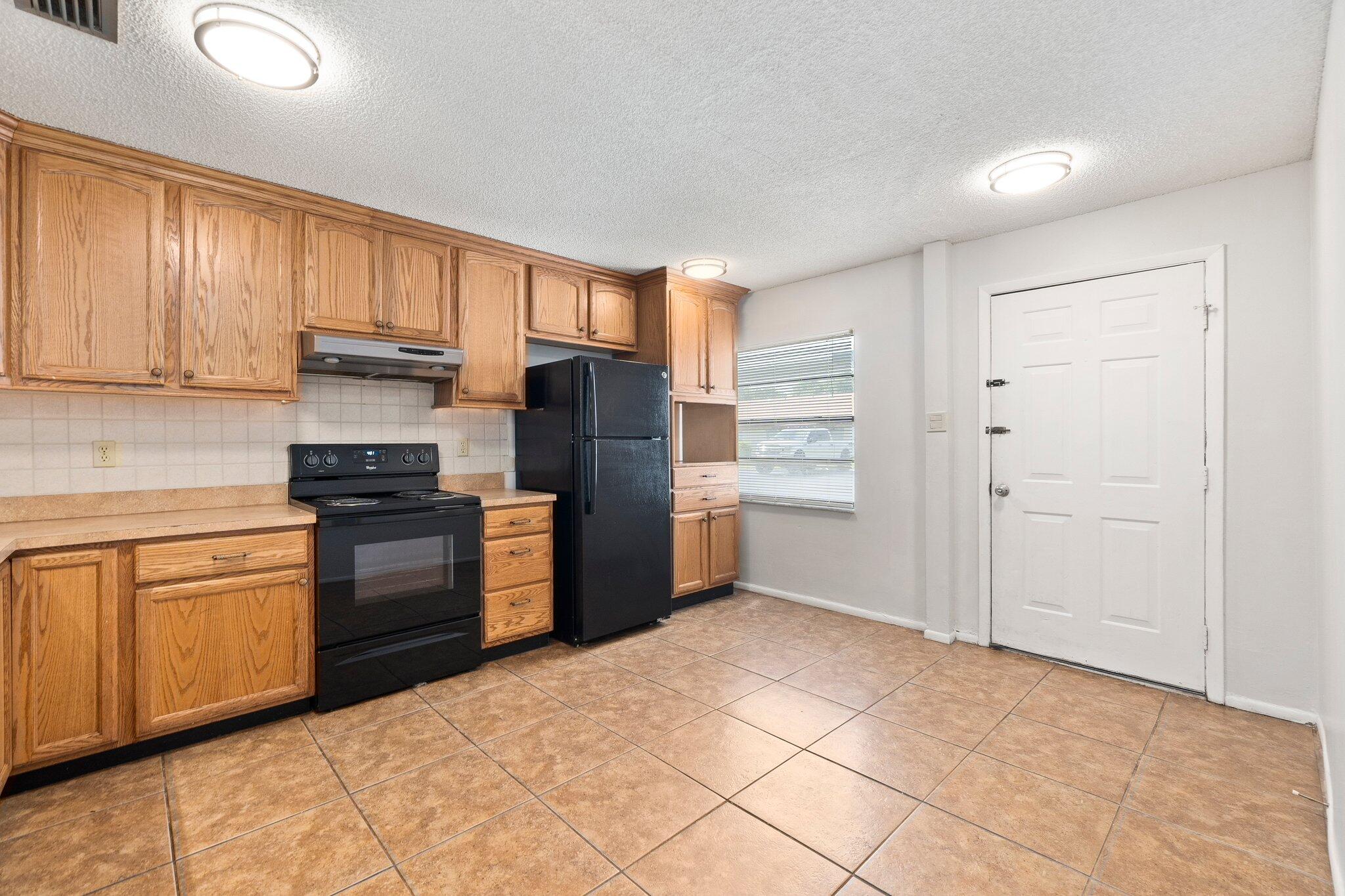 6012 Indrio Road, Unit E2 Fort Pierce, FL 34951 - Photo 12 of 25 a kitchen with a refrigerator sink and cabinets