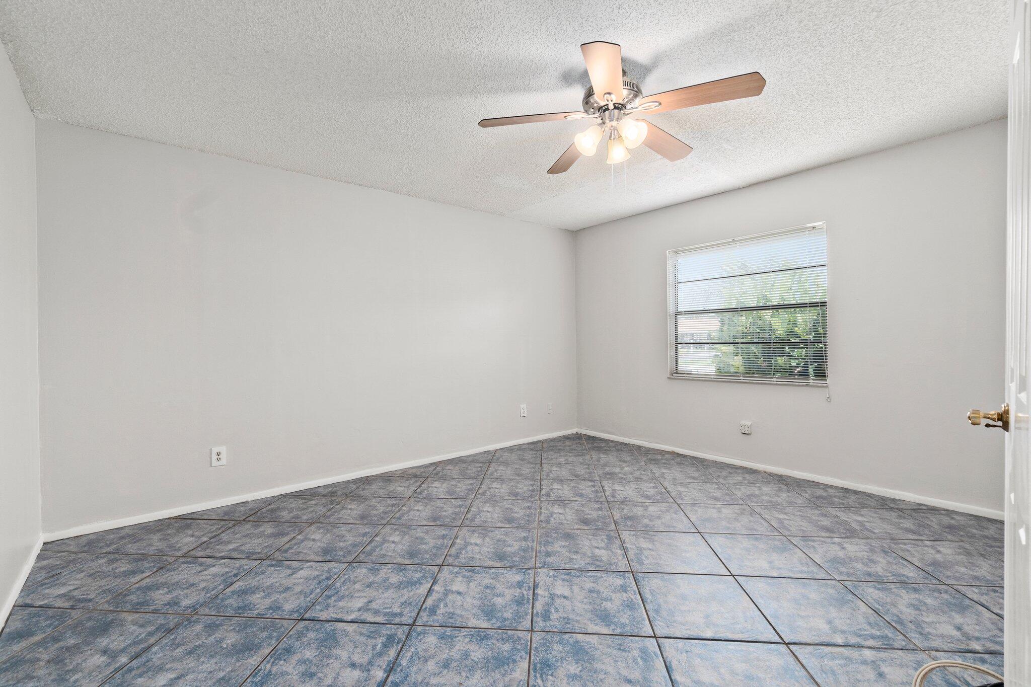 6012 Indrio Road, Unit E2 Fort Pierce, FL 34951 - Photo 13 of 25 an empty room with windows and ceiling fan