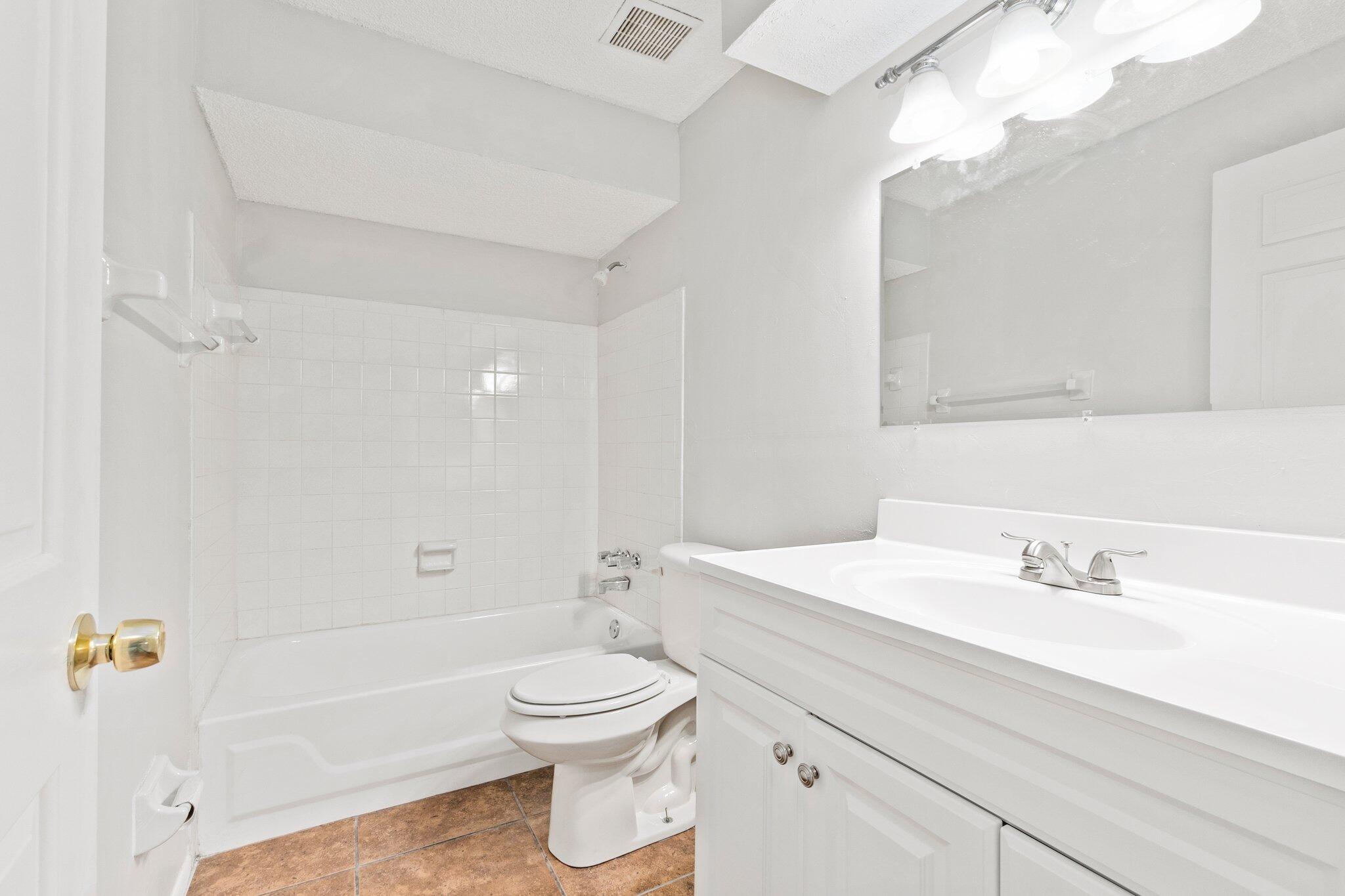 6012 Indrio Road, Unit E2 Fort Pierce, FL 34951 - Photo 19 of 25 a bathroom with a sink a toilet and shower