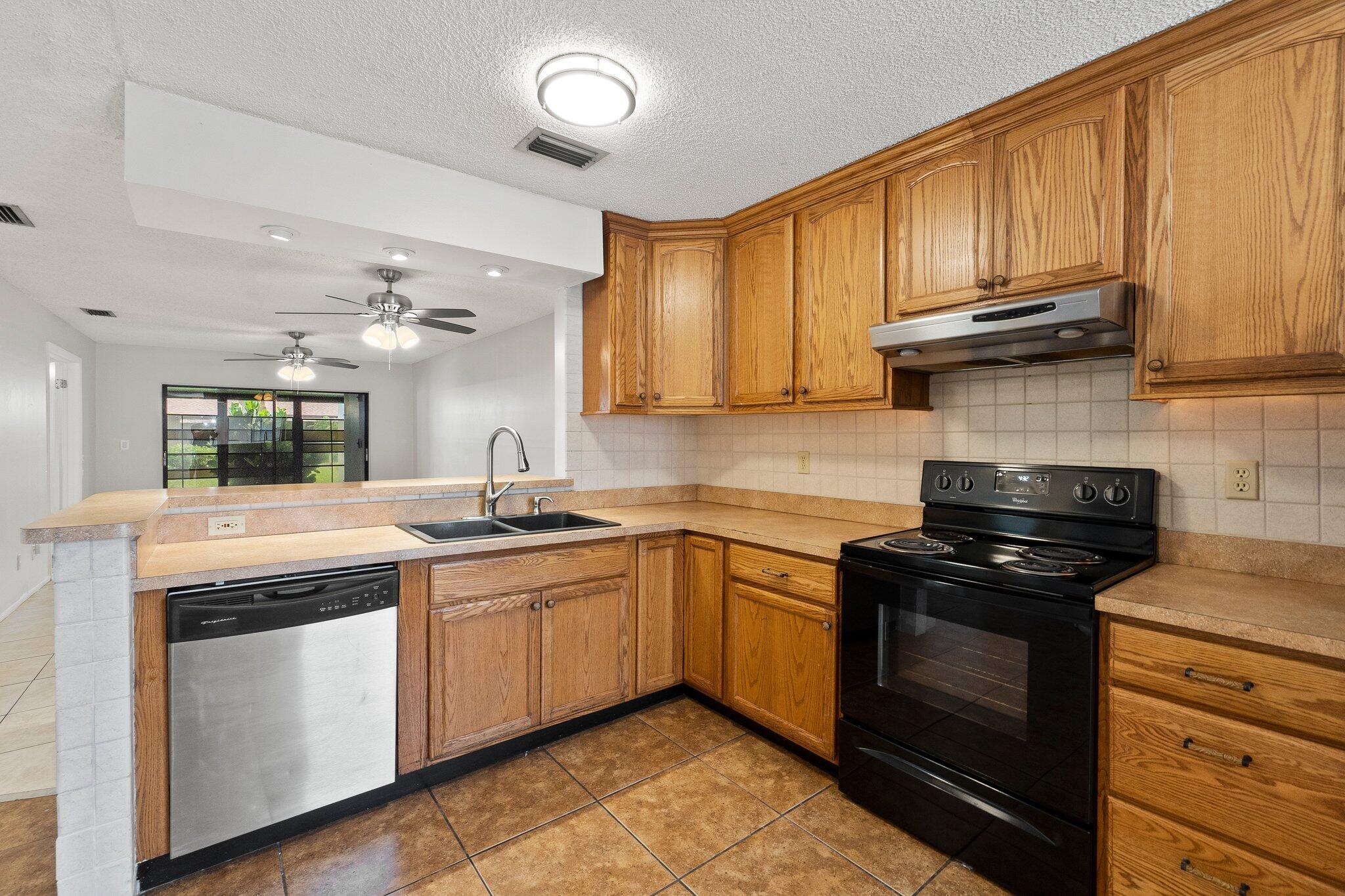 6012 Indrio Road, Unit E2 Fort Pierce, FL 34951 - Photo 10 of 25 a kitchen with granite countertop wooden cabinets and a stove top oven