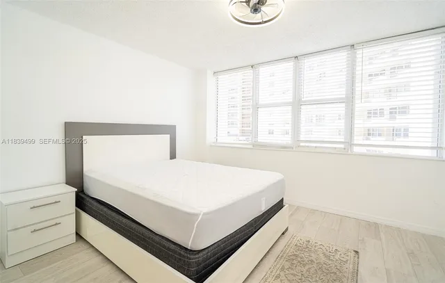 a white bed sitting in a bedroom next to a window