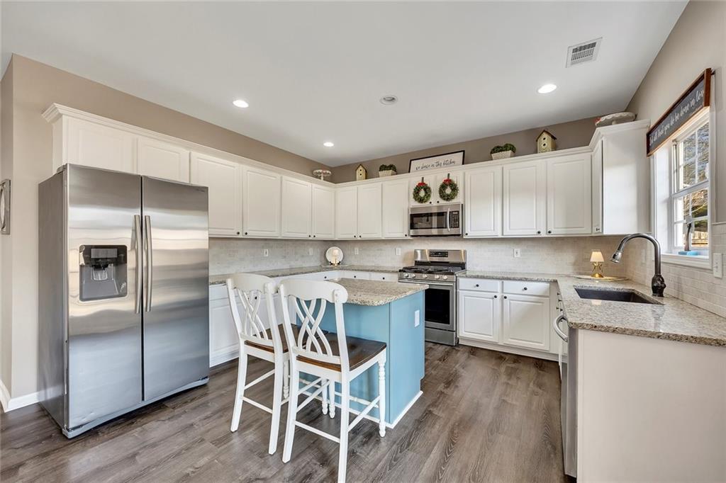 605 Garnet Court Canton, GA 30114 - Photo 20 of 75 a kitchen with stainless steel appliances granite countertop a refrigerator a stove a sink dishwasher and white cabinets with wooden floor