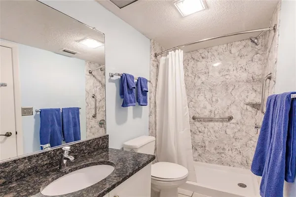 a bathroom with a granite countertop sink toilet and shower
