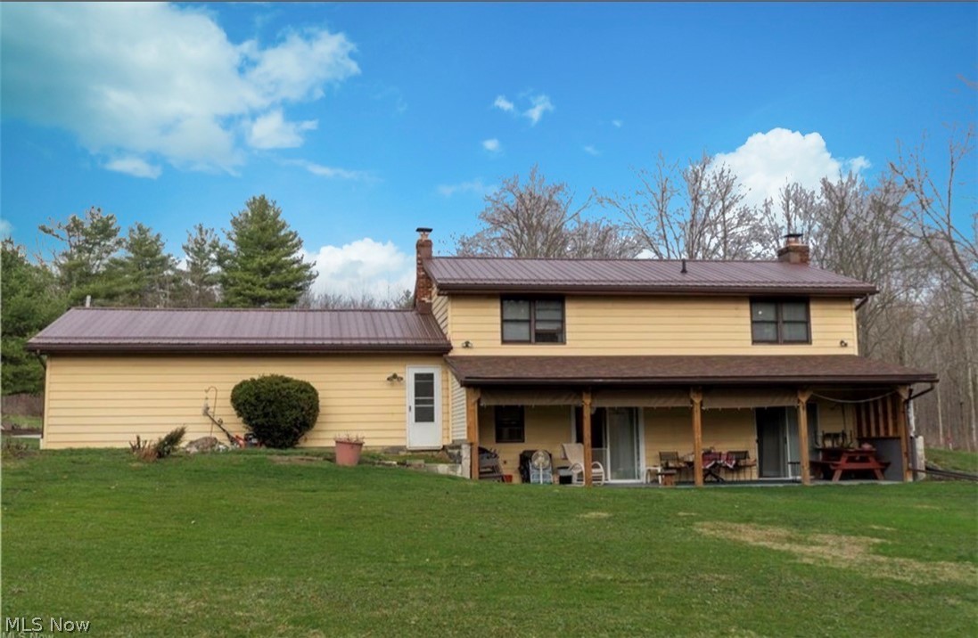 871 South County Line Road Geneva, OH 44041 - Photo 4 of 20 Rear view of house featuring a chimney, a lawn, and a metal roof