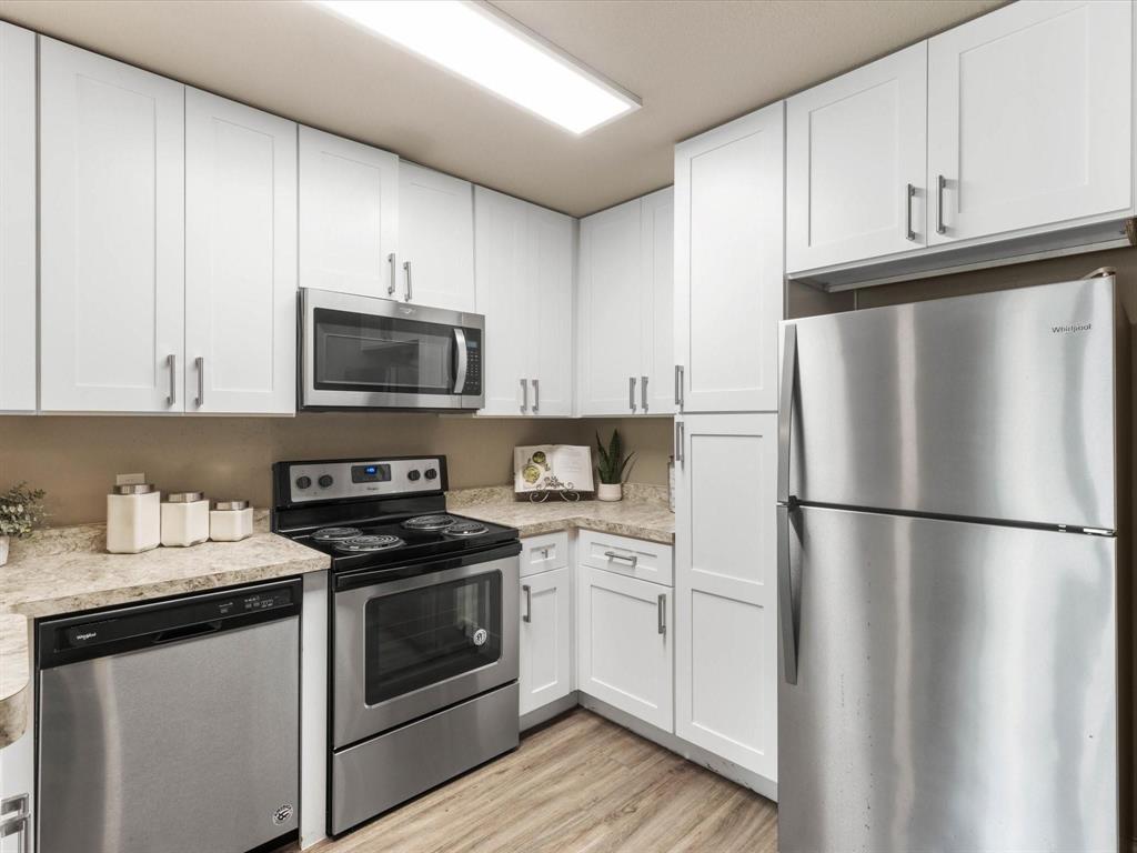 6108 Abrams Road, Unit 505 Dallas, TX 75231 - Photo 11 of 20 a white kitchen with stainless steel appliances and white cabinets