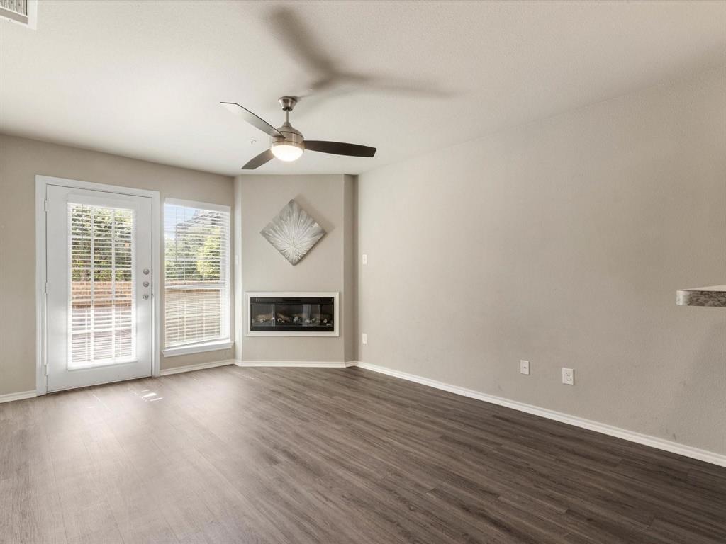 6108 Abrams Road, Unit 505 Dallas, TX 75231 - Photo 4 of 20 a view of an empty room with wooden floor fireplace and a window
