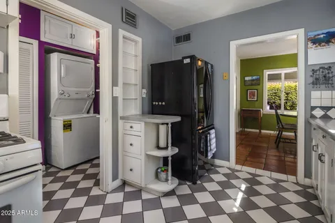 a room with a black white checkered floor with a dining table and a refrigerator