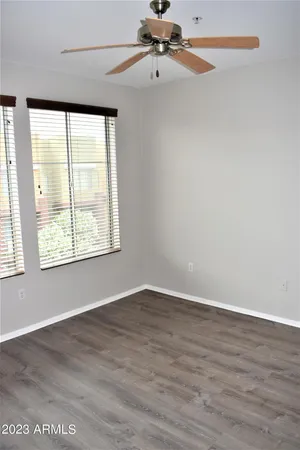 an empty room with wooden floor fan and windows