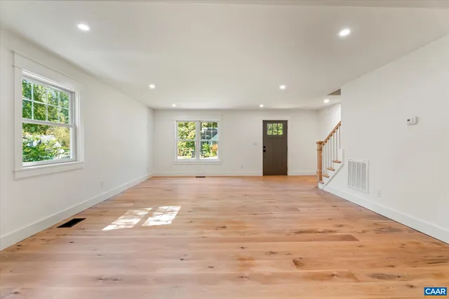 a view of an empty room with wooden floor and windows