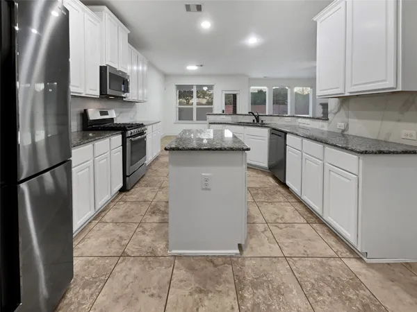 a kitchen with stainless steel appliances granite countertop a refrigerator and a stove top oven