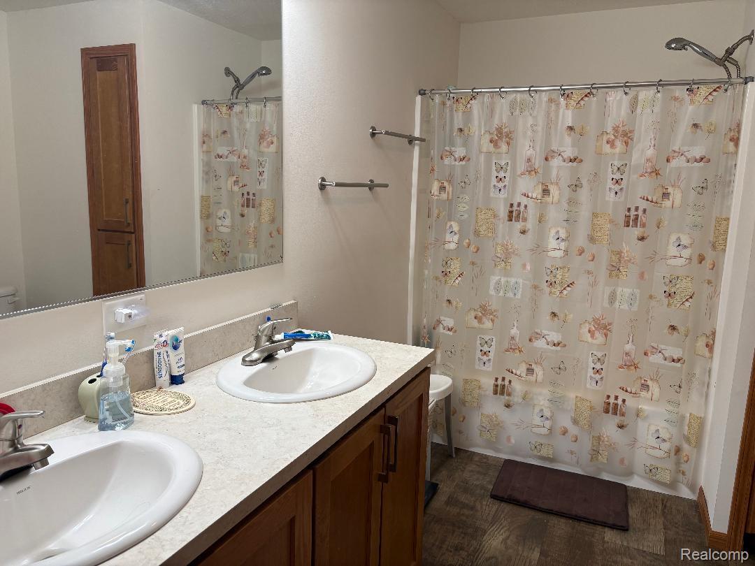 3615 Pineland Point Road Gladwin, MI 48624 - Photo 18 of 25 Full bath featuring double vanity, dark wood-style flooring, and shower / bathtub combination with curtain