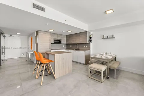 a kitchen with a dining table chairs and refrigerator