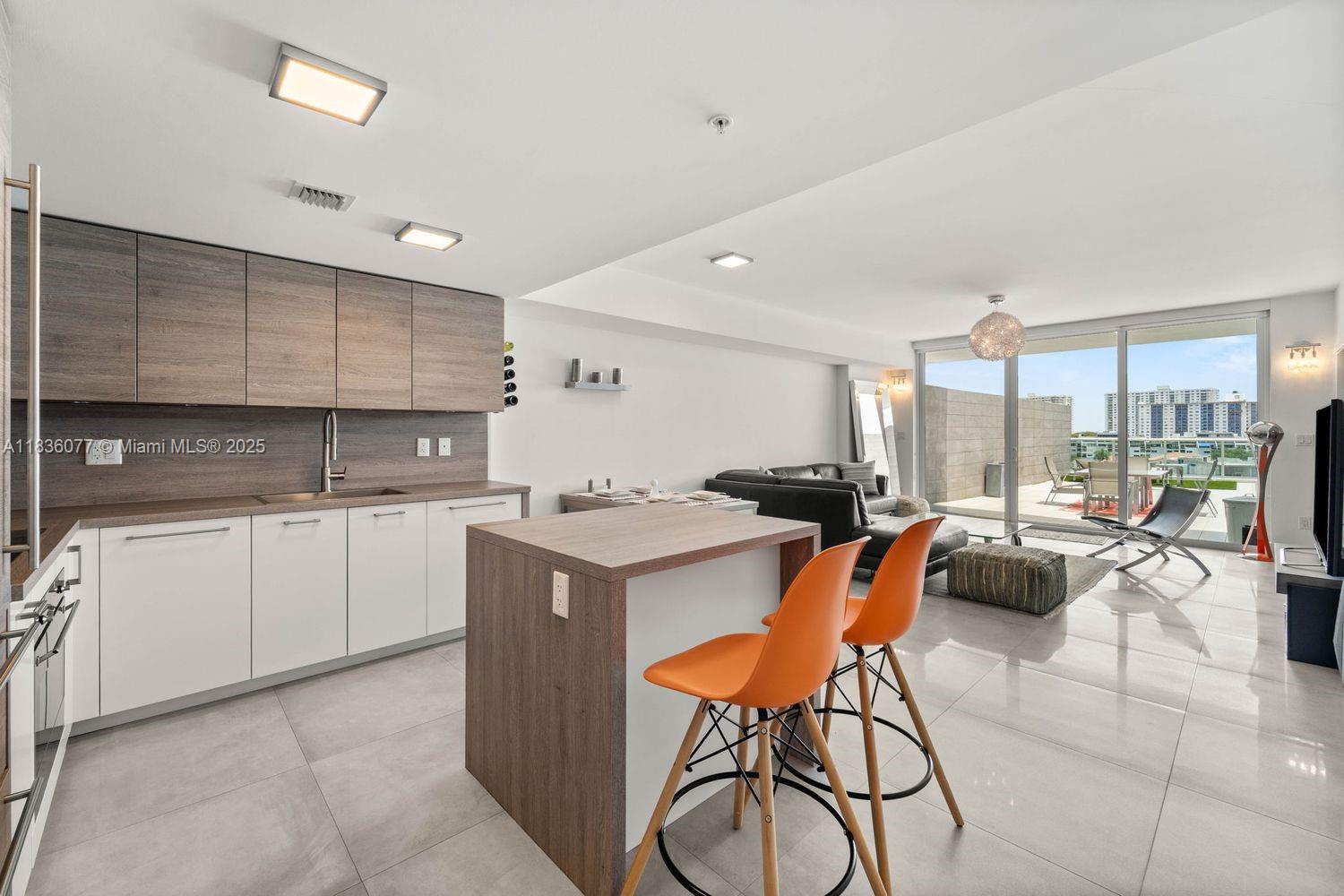 400 Sunny Isles Boulevard, Unit 616 Sunny Isles Beach, FL 33160 - Photo 5 of 19 a kitchen with stainless steel appliances kitchen island granite countertop a table chairs in it and a large window
