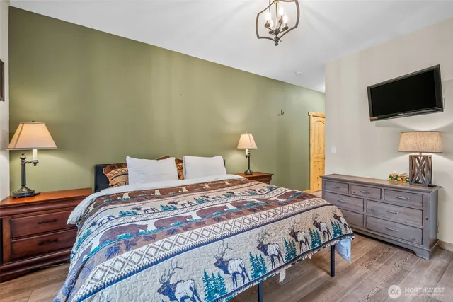 a bedroom with a bed and a flat tv screen on dresser